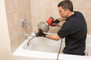 Plumber unclogging tub drain